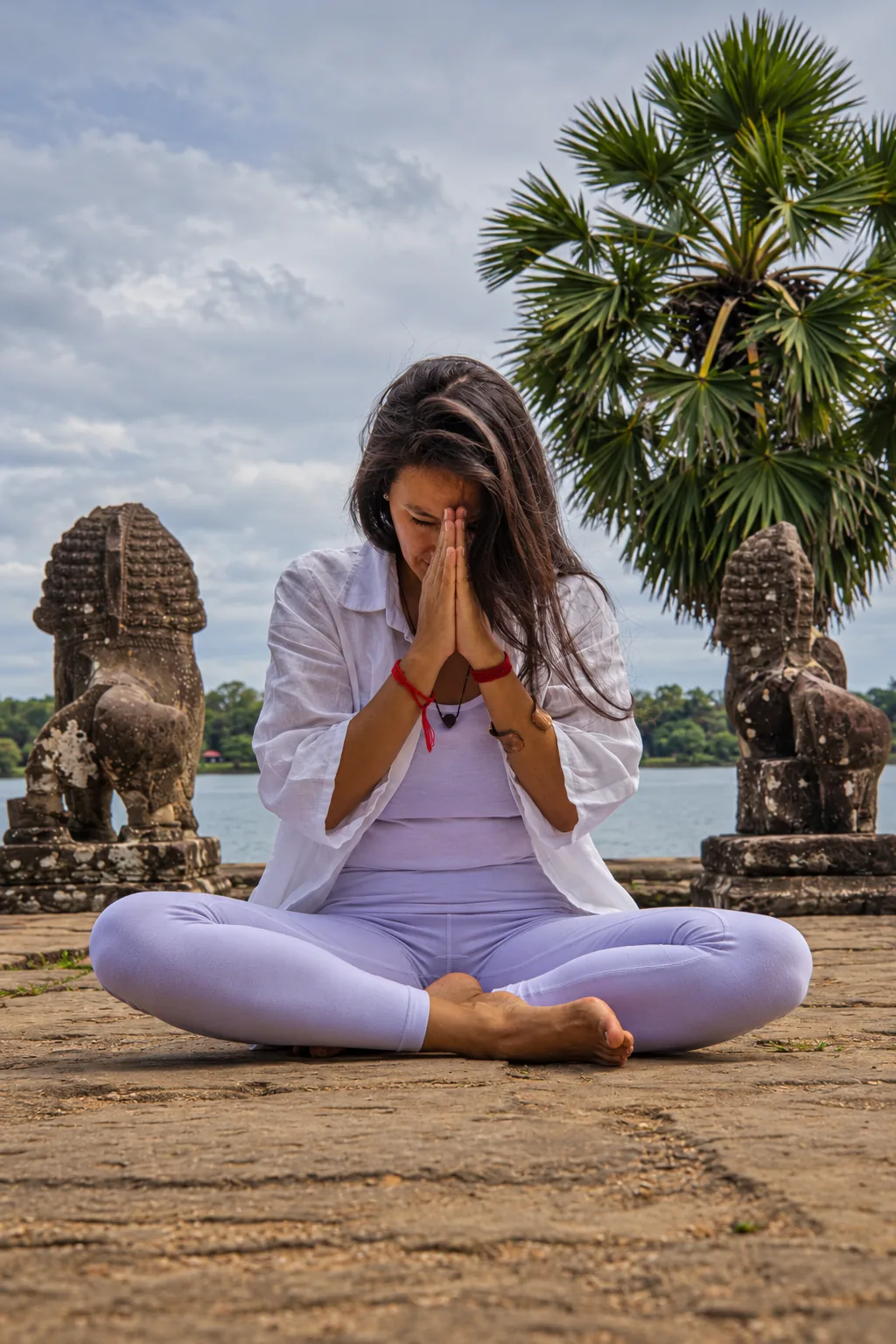 Marielisa Padilla seated with hands in prayer, eyes closed